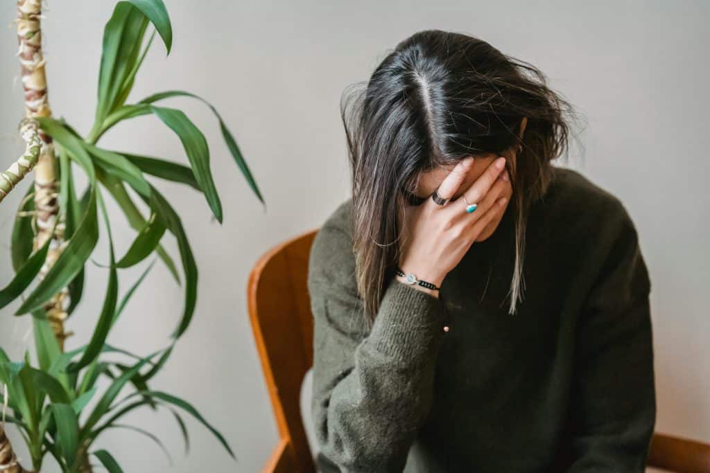 Jeune femme assise sur une chaise qui se tient la tête dans une main