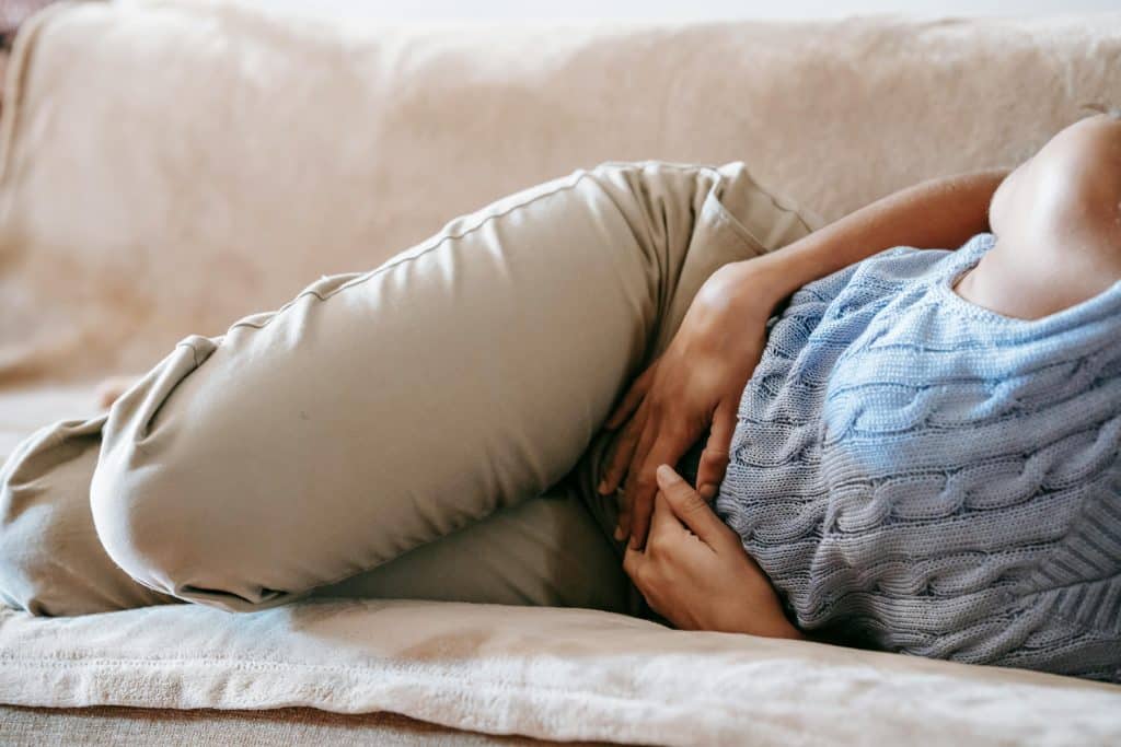 Femme allongée sur son canapé, les mains posées sur son ventre