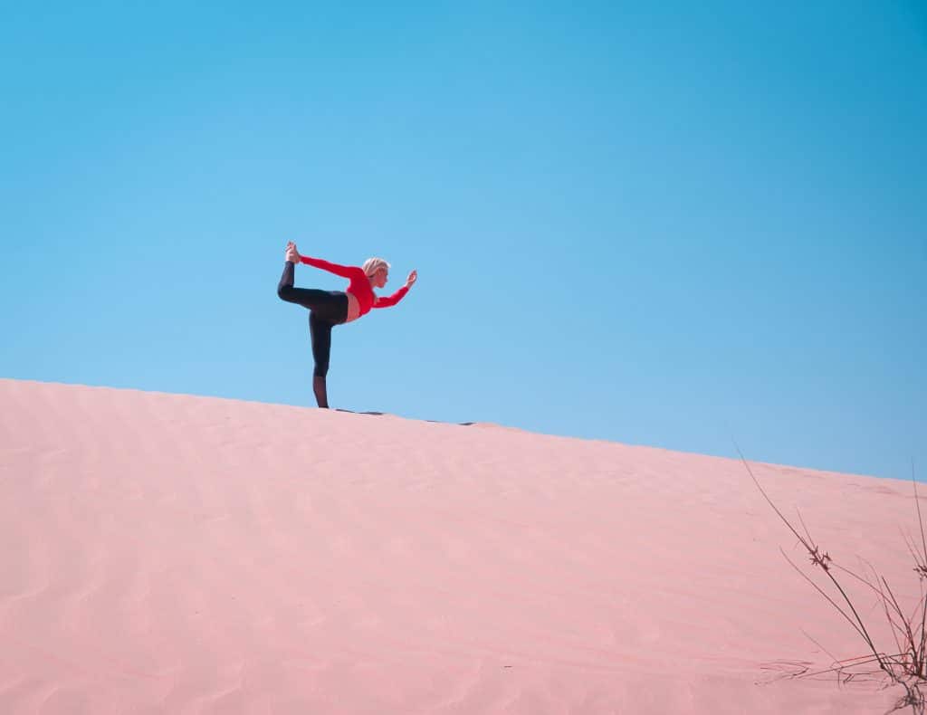 Femme d'âge mûr en train de réaliser des étirements sur une dune