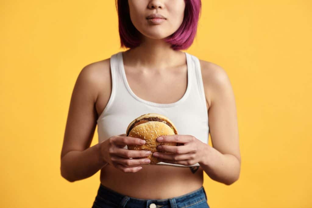 Femme qui tient un hamburger dans ses deux mains