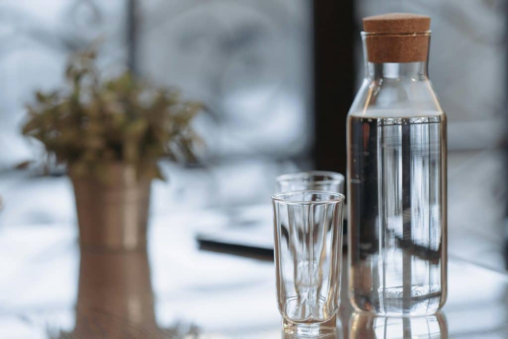 Carafe d'eau en verre posée sur une table avec deux verres