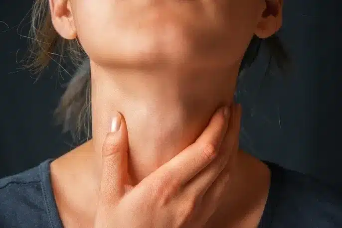 Femme qui pose sa main au niveau de la thyroïde