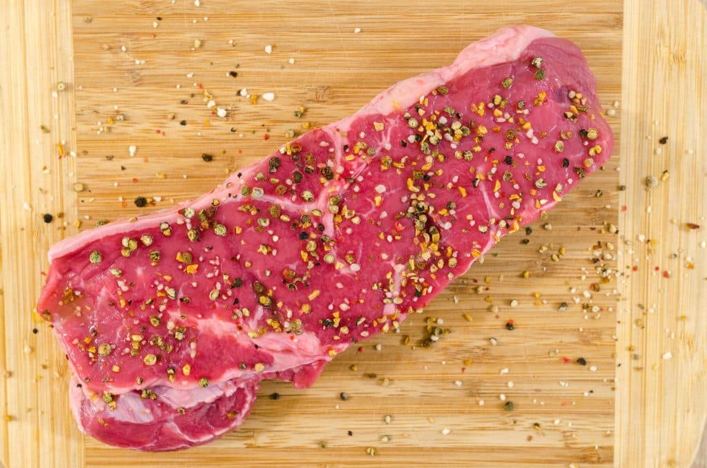 morceau de viande rouge sur une planche en bois, aliment pro-inflammatoire